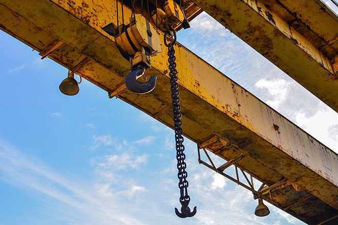 Overhead crane hook and chain against the sky