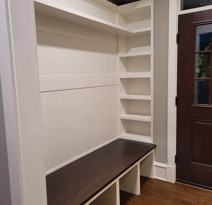 Mudroom shelves and built-in dark stained bench furnished with baskets and hooks 