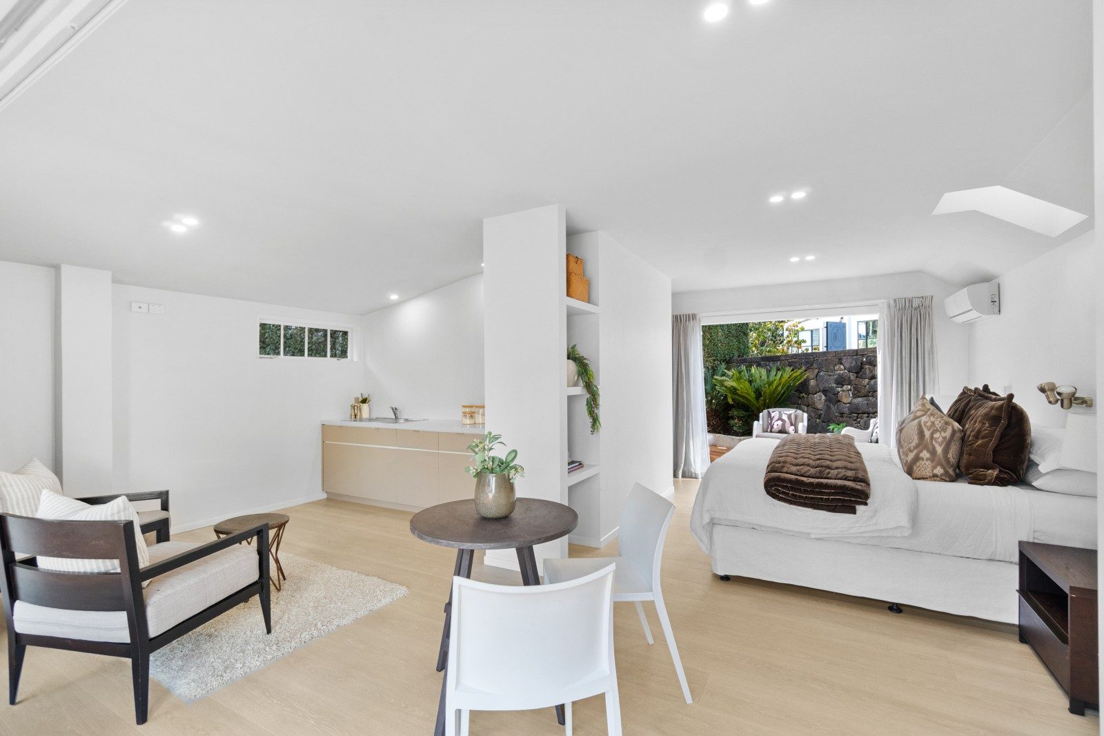 Open-plan room at Owens Road with a bed, dining table, seating area and compact kitchen