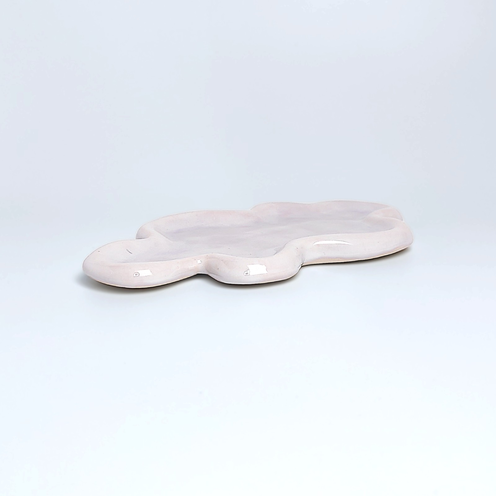 Unique handmade ceramic plate shaped like a cloud, featuring soft pastel pink glazing and an organic sculptural form