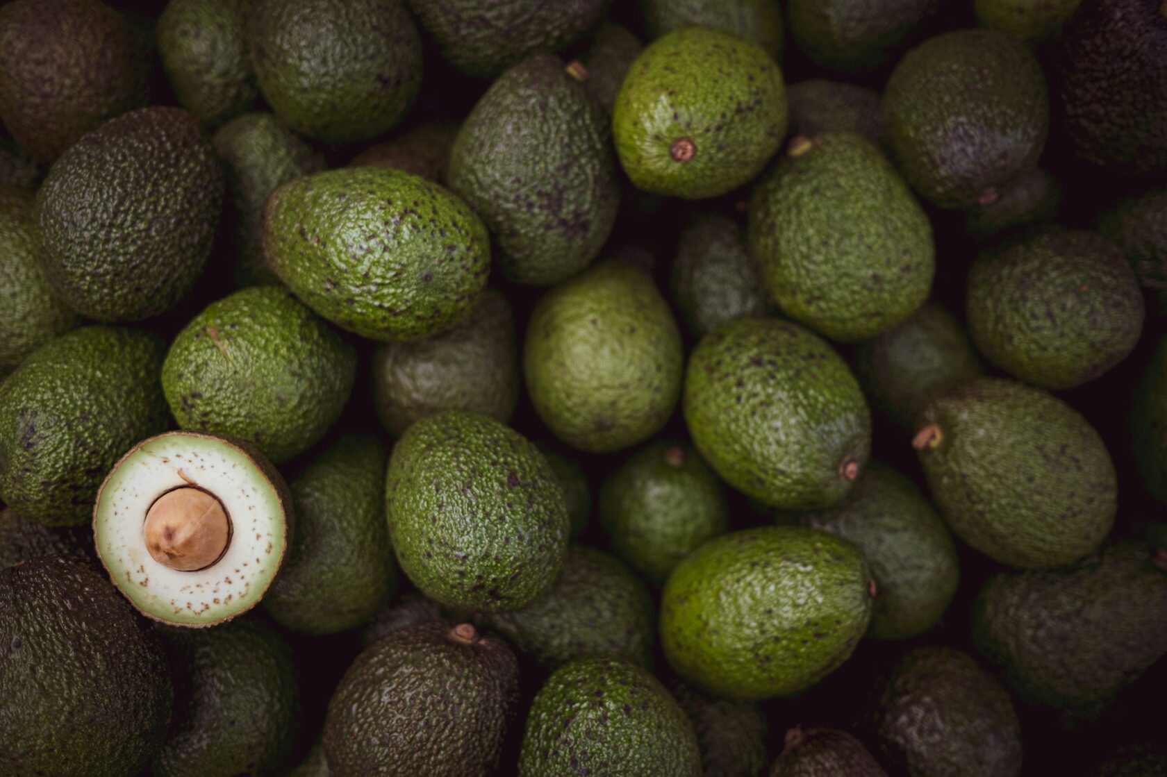 A box being packed with fresh avocados, limes and strawberries.