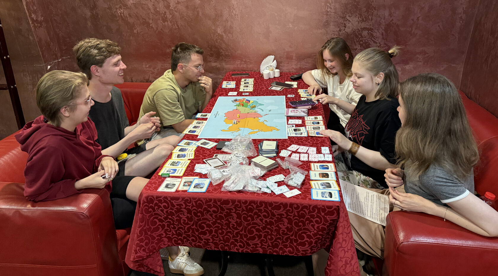 Участники играют в настольную игру «Познавай Россию» за столом