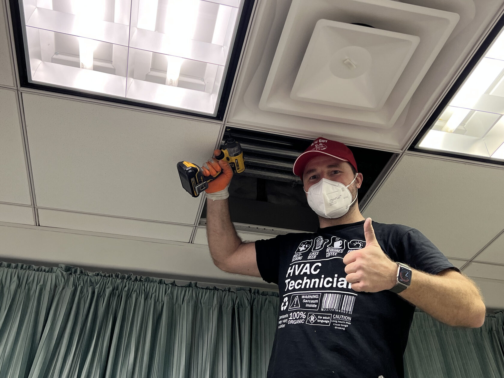 HVAC technician working at a ceiling air grille