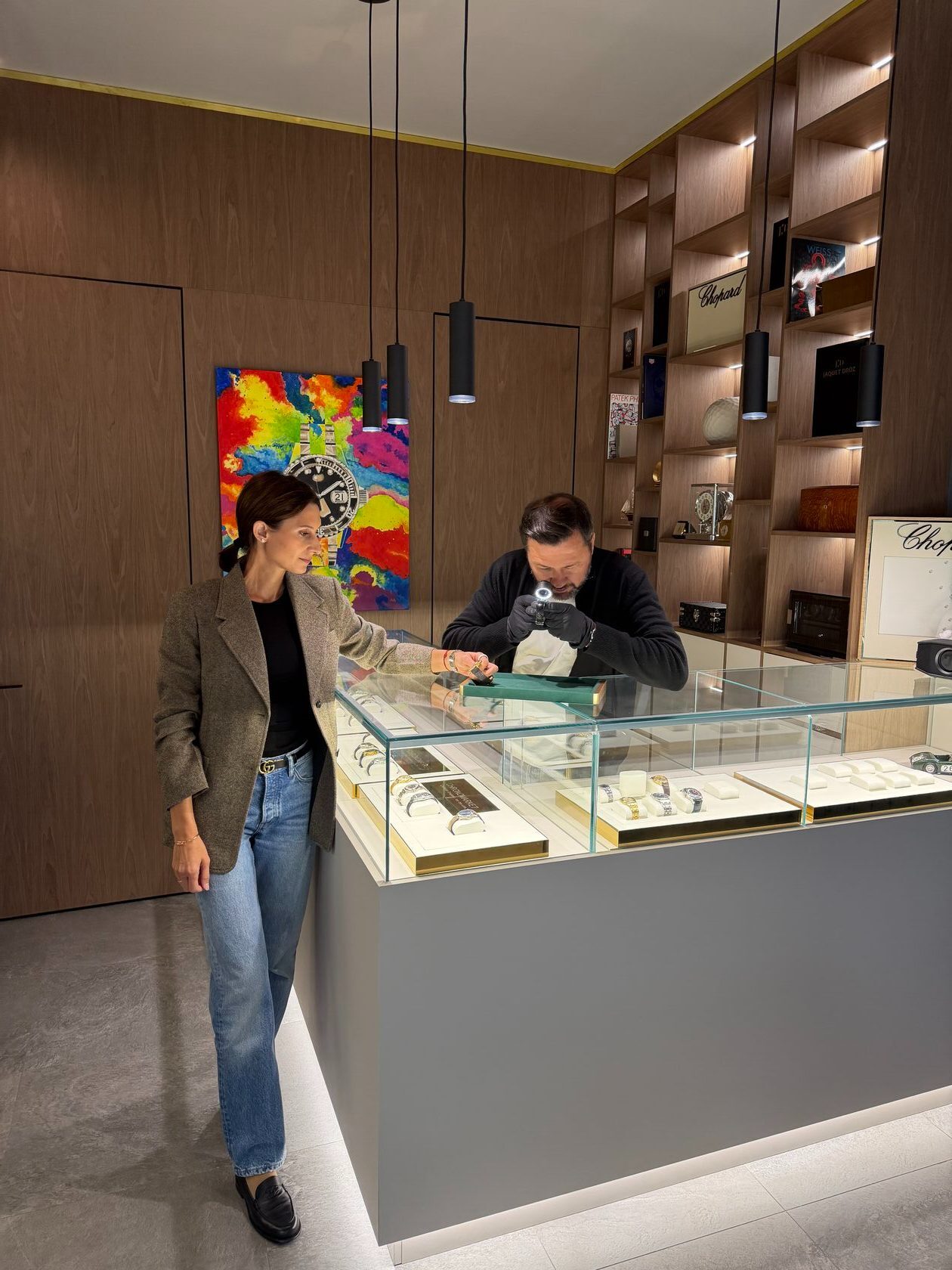 Viacheslav Fisenko prüft eine Uhr mit der Lupe, Anna Fisenko daneben – ChronoMarket Berlin