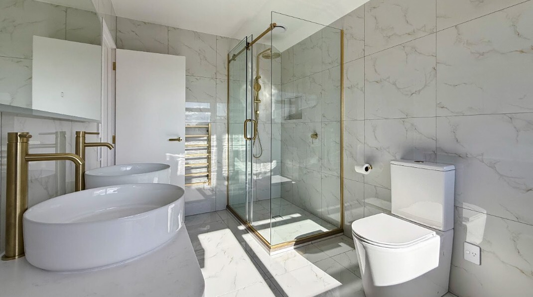 Renovated ensuite with double basins, marble-look tiles and brass shower fittings