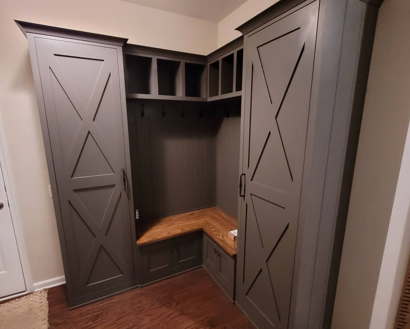 Diagonal view of farm house style mudroom cabinets with built-in bench in dark grey color