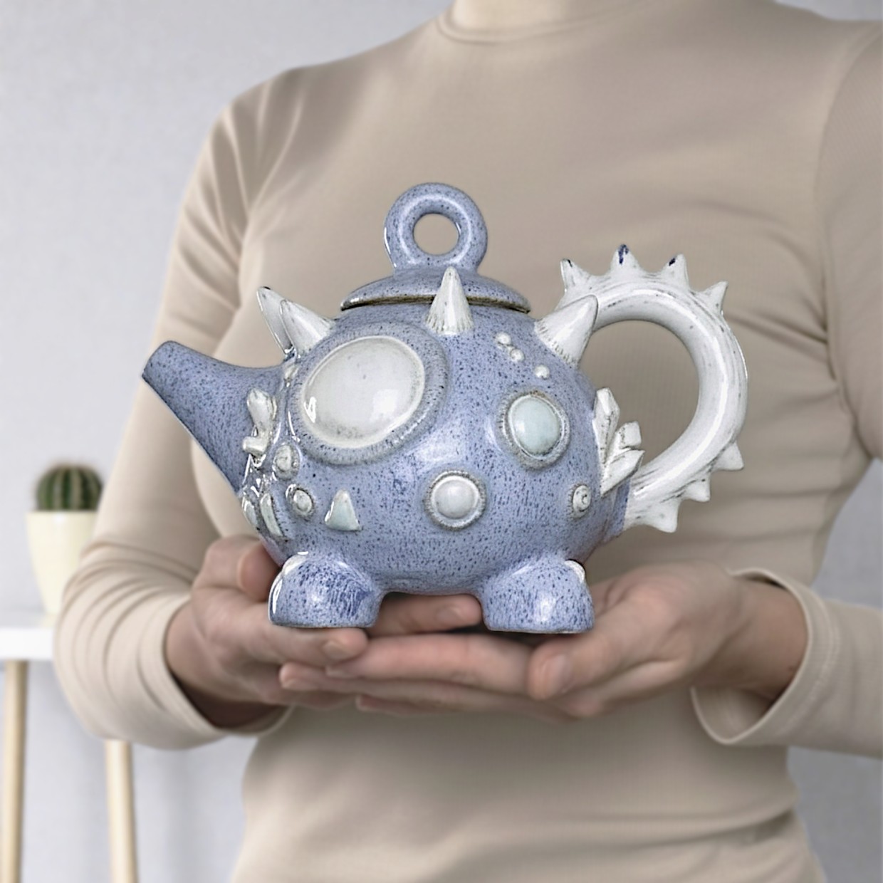 Handcrafted ceramic teapot shaped like a fantasy creature with horns and crystals, in blue and white tones, part of a tea set with two cups and saucers