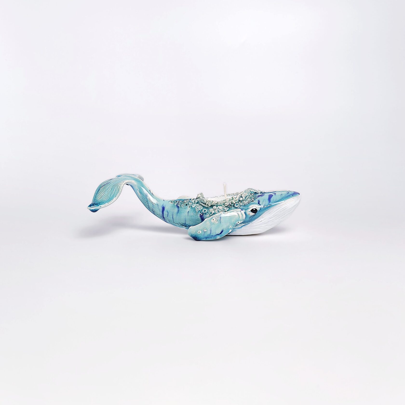 Unique handmade ceramic whale candle holder with ocean-blue glaze, detailed sculptural texture, and a built-in candle