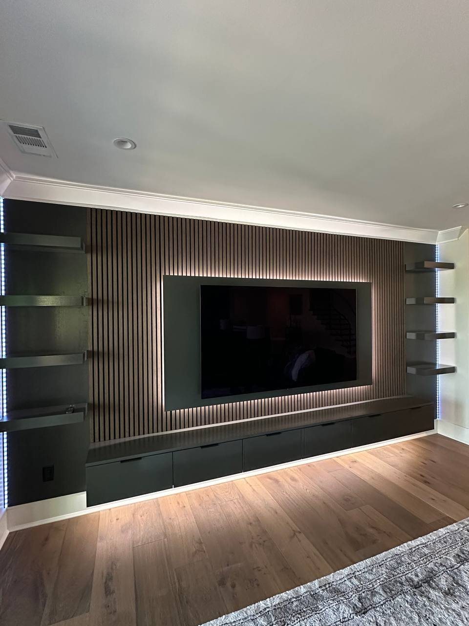 Full slat media wall with floating cabinet, lit shelves and hidden TV wiring