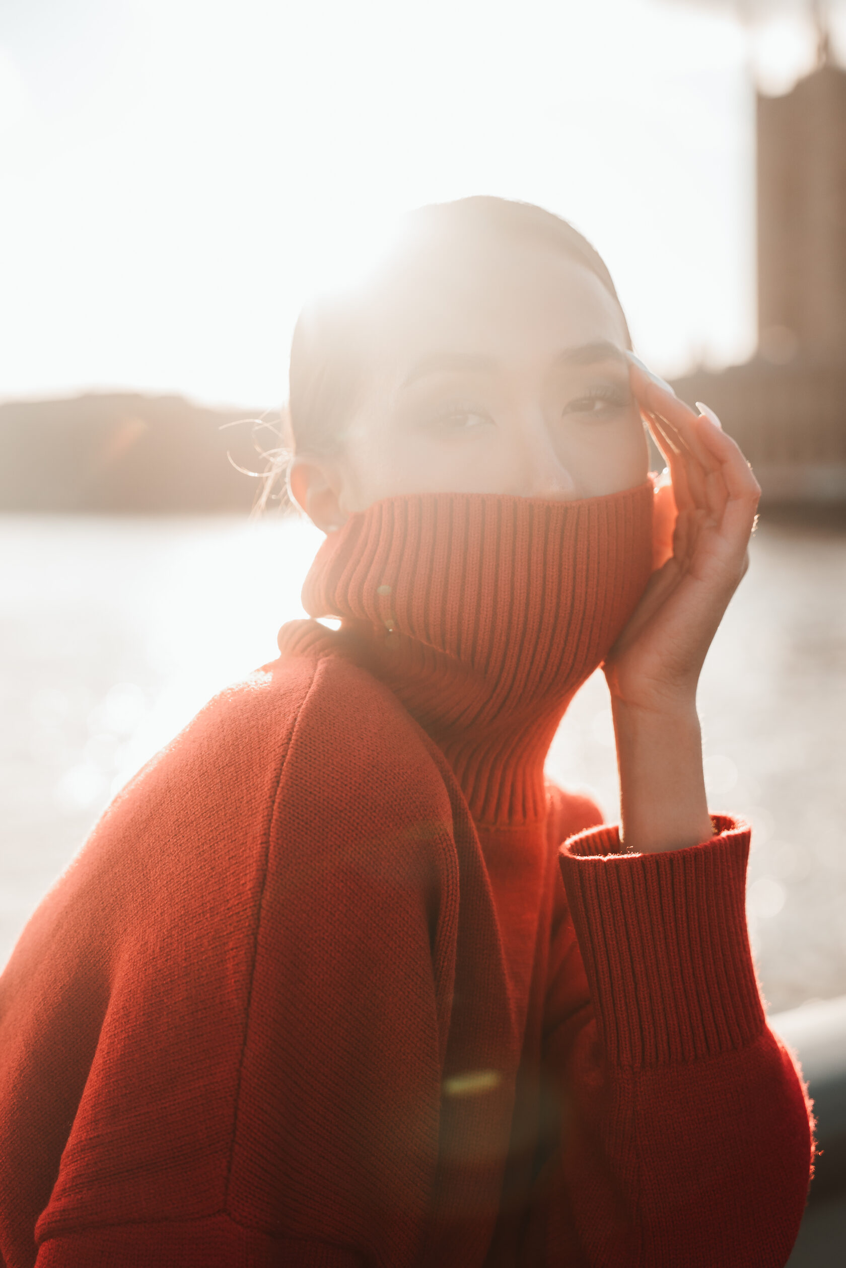 Sunlight falling across a portrait of a woman in a red knit jumper