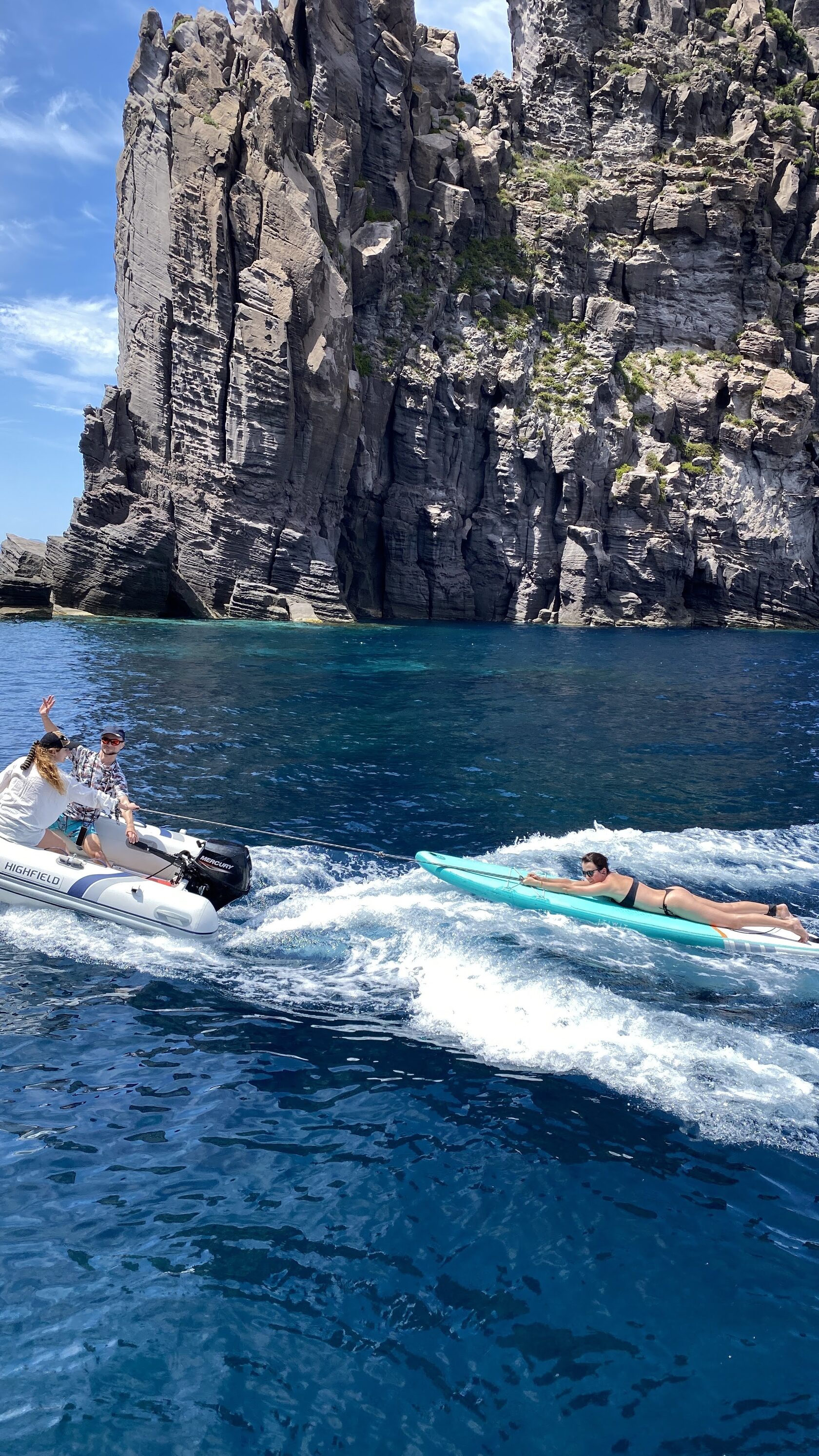 Dinghy speeding along dark volcanic cliffs