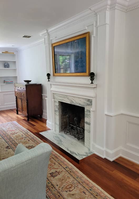 Living room fireplace with historic paneling and built-in shelves.
