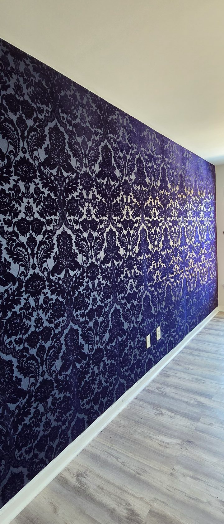 Navy damask wallpaper installed on a long accent wall