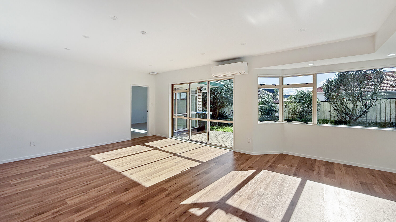 Sunlit St Heliers living room with timber flooring and windows facing the garden.