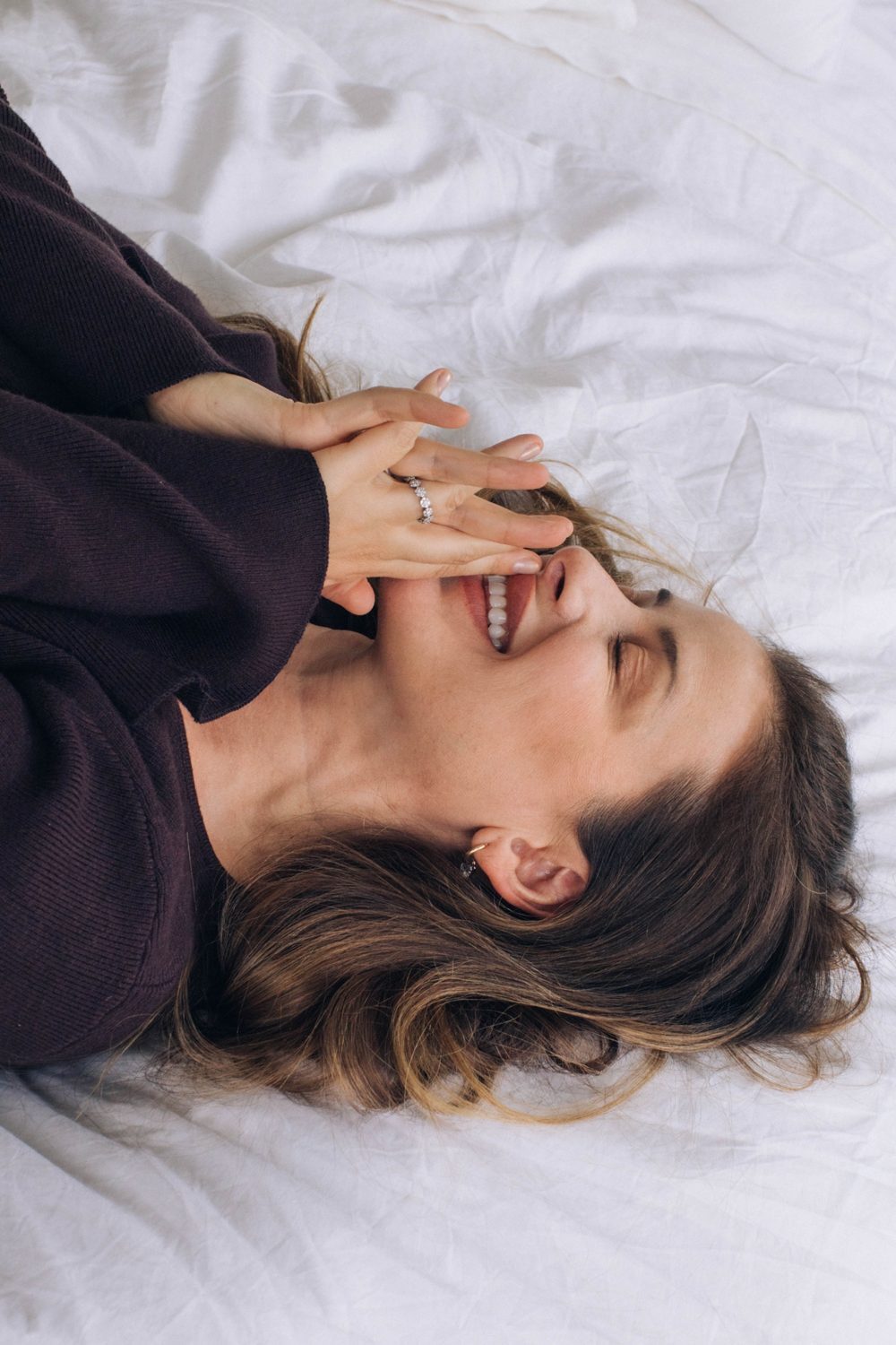 Lo laughing, lying on white sheets