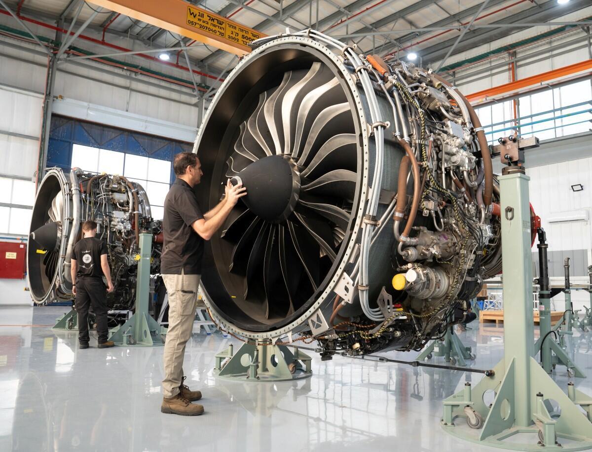 Technician inspecting a turbofan engine in a repair station hangar