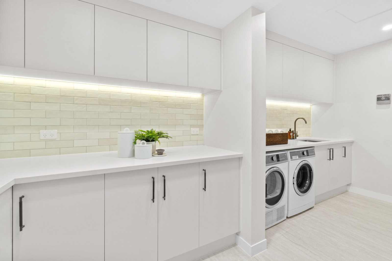 Renovated Owens Road laundry with white cabinetry, a sink, washing machine and dryer