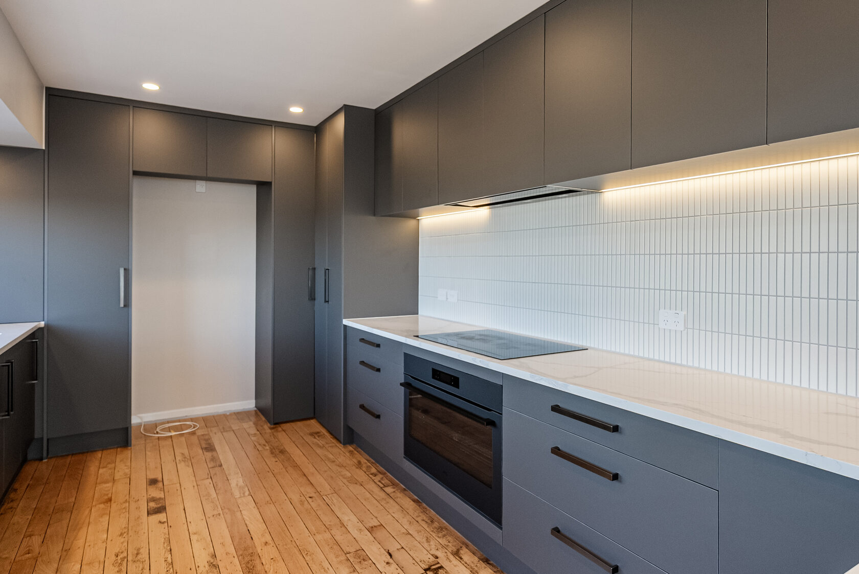 Dark full-height cabinetry, drawers and pale benchtops in the renovated Glenfield kitchen