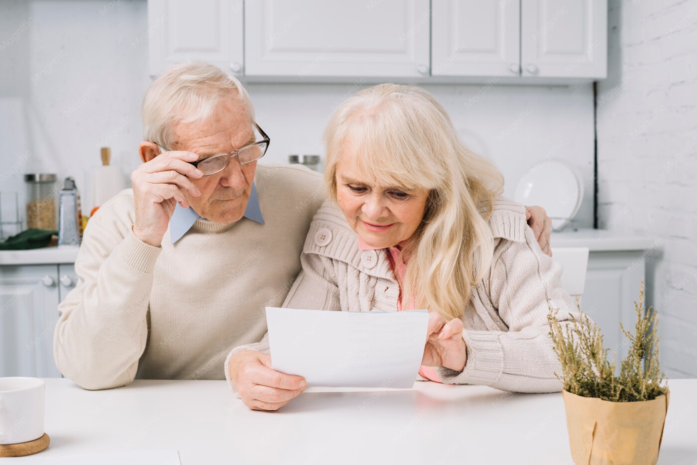 Una coppia di pensionati legge insieme un documento in cucina