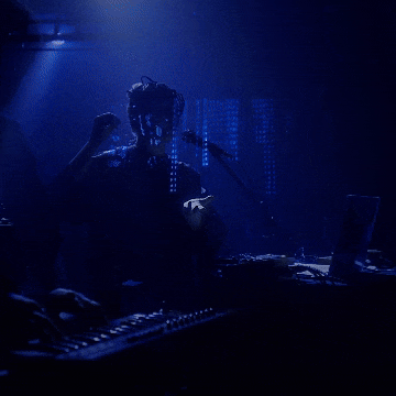 A performer on a dark stage lit in blue
