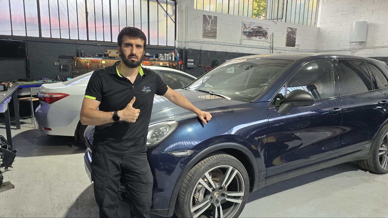 Ahmad, électricien automobile Way Master, devant le Porsche Cayenne Hybrid