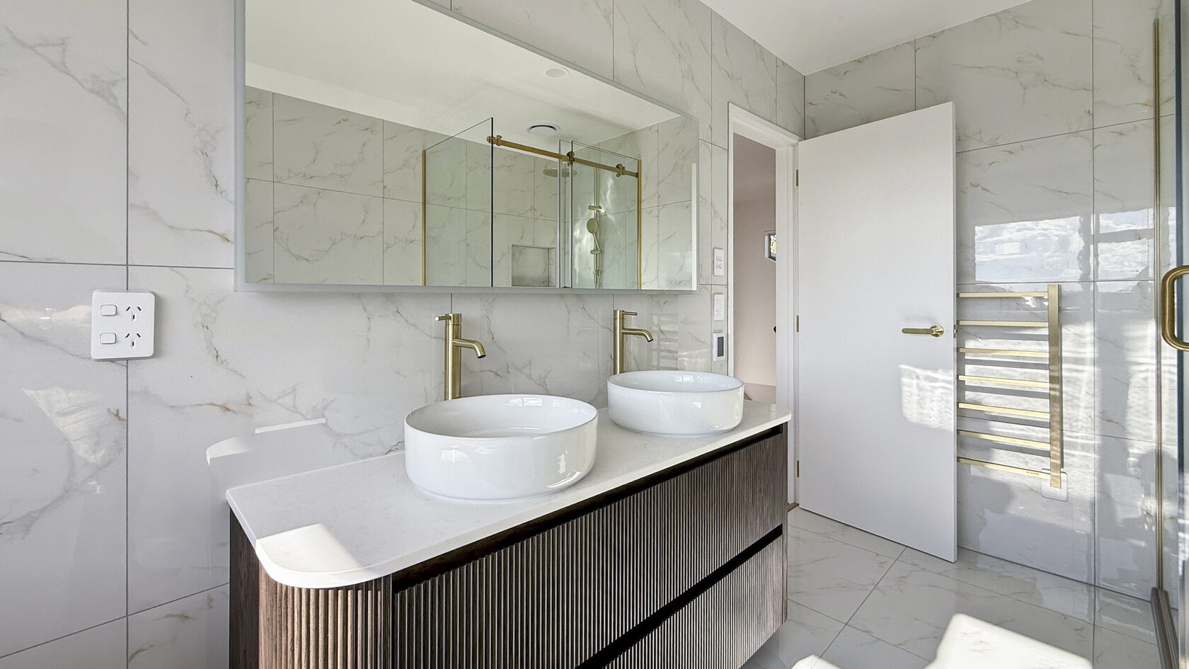 Double vessel sinks on a floating timber vanity in a St Heliers bathroom.
