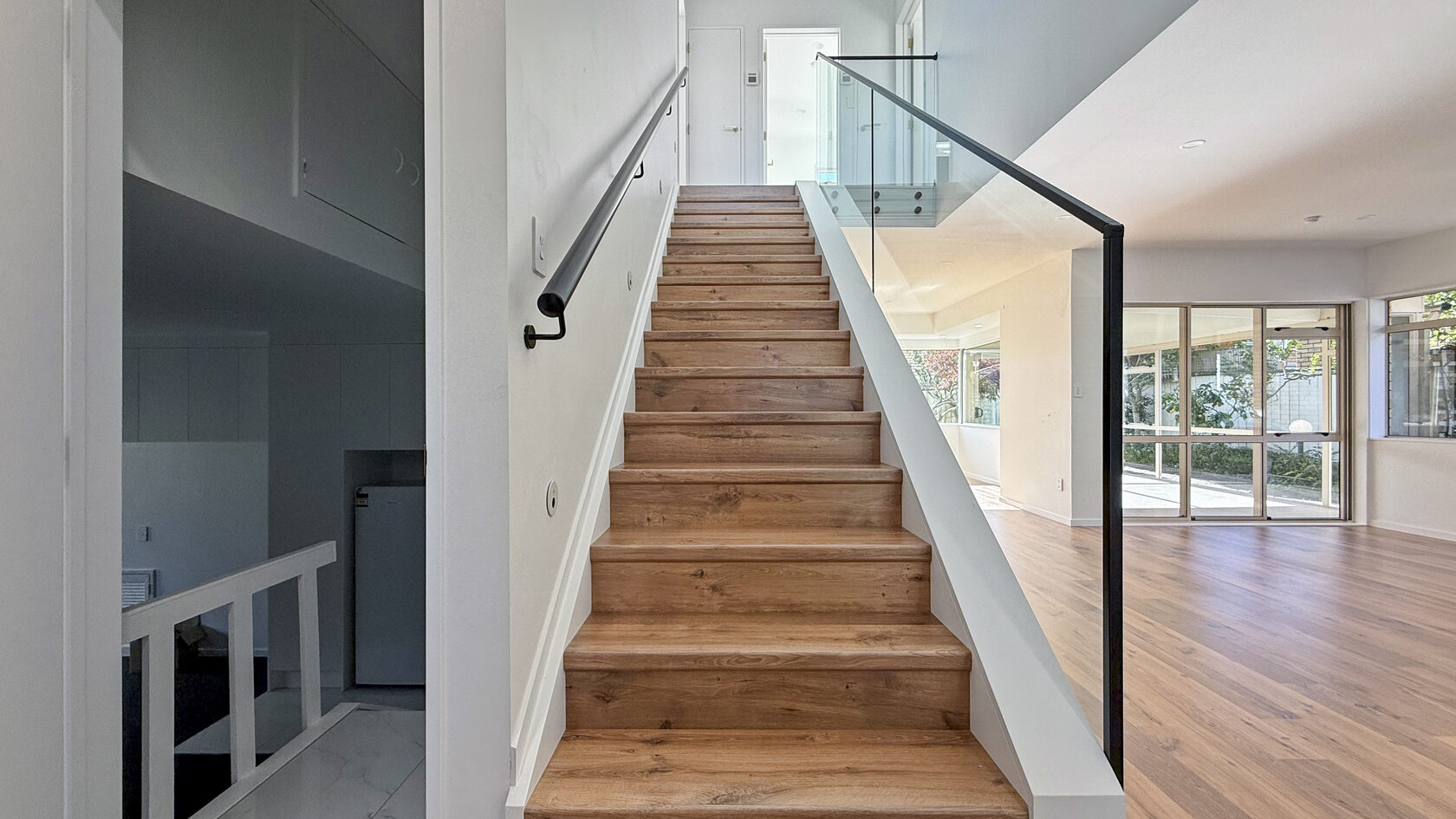 Renovated timber staircase with a clear glass balustrade in a St Heliers home.