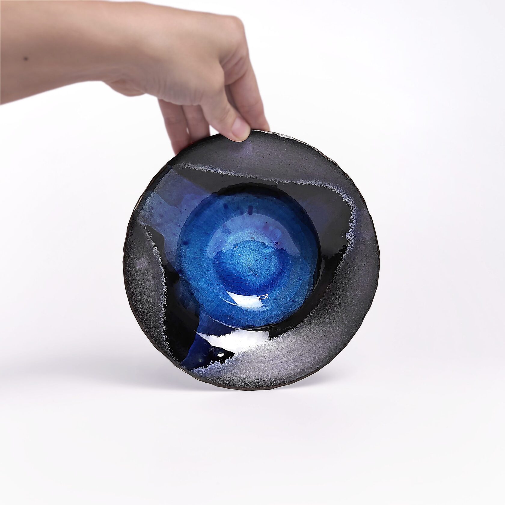 Handmade decorative ceramic plate with deep blue glossy glaze and black clay base