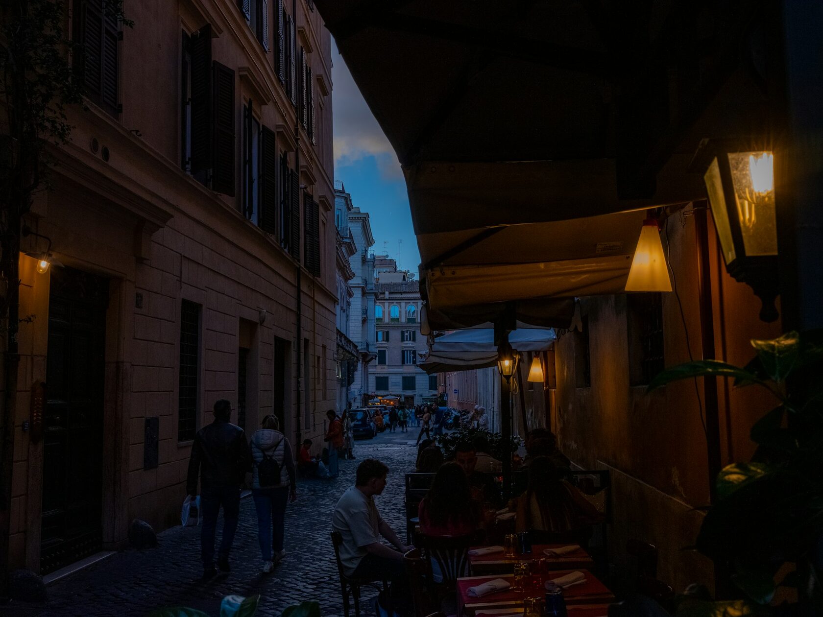 The Colosseum glowing in warm golden-hour light, a quiet cobbled street leading toward it