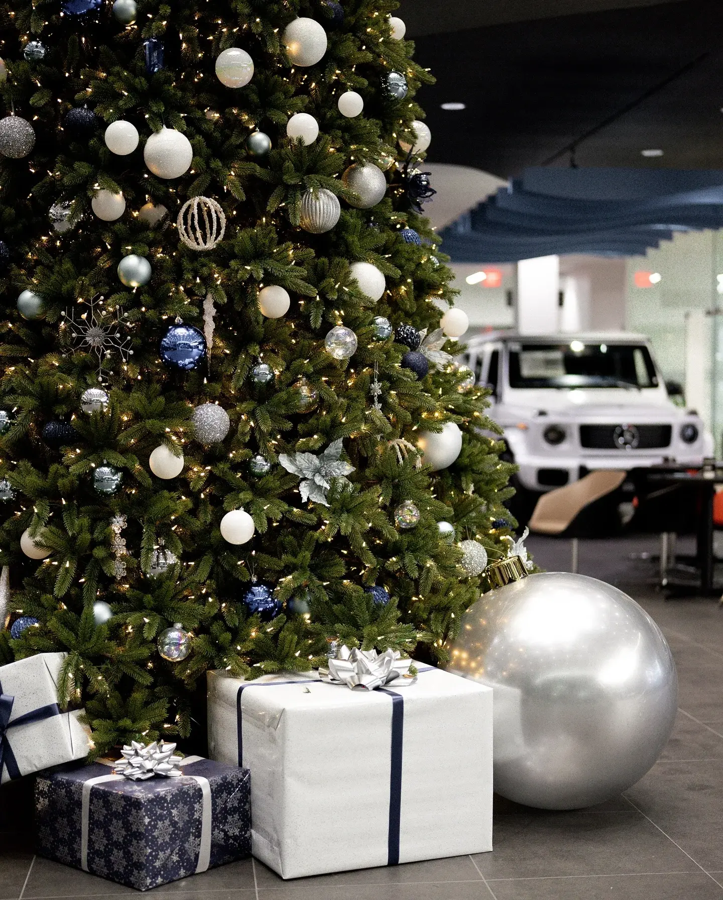 Holiday tree with oversized ornaments and wrapped gifts at its base