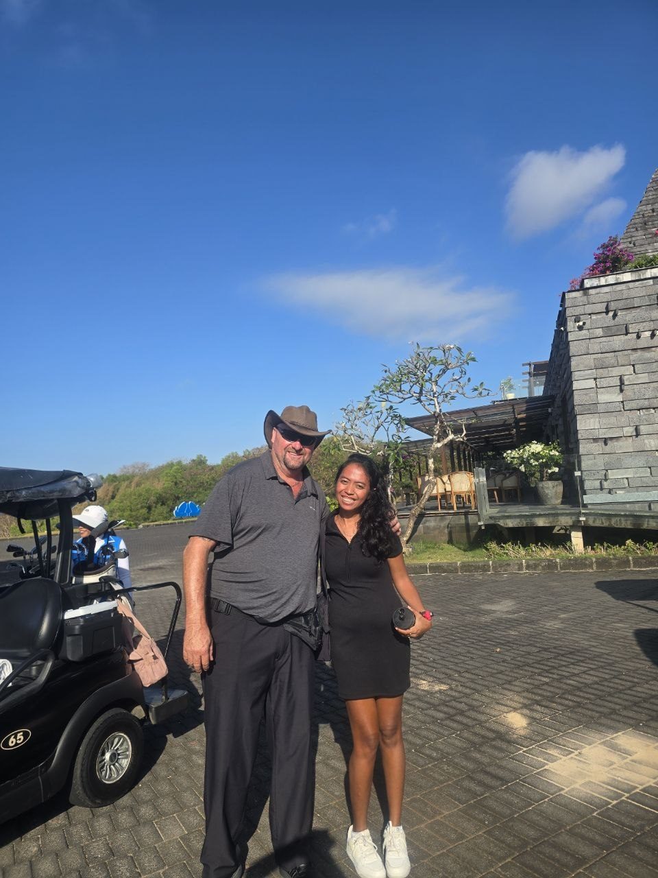 Golfer with a member of the club team next to a golf cart