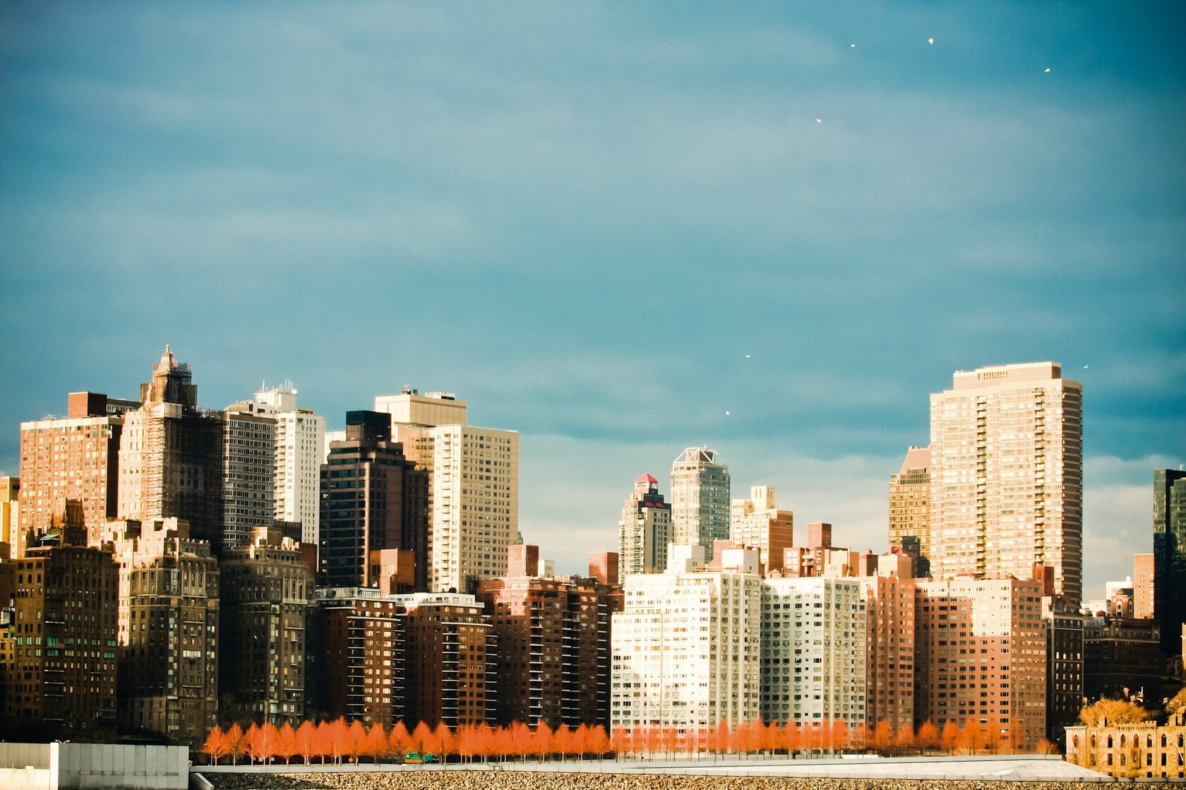 City skyline in daylight — towers and streets bathed in warm afternoon sun