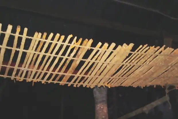 Split lengths laid out to dry on a rack under a roof.