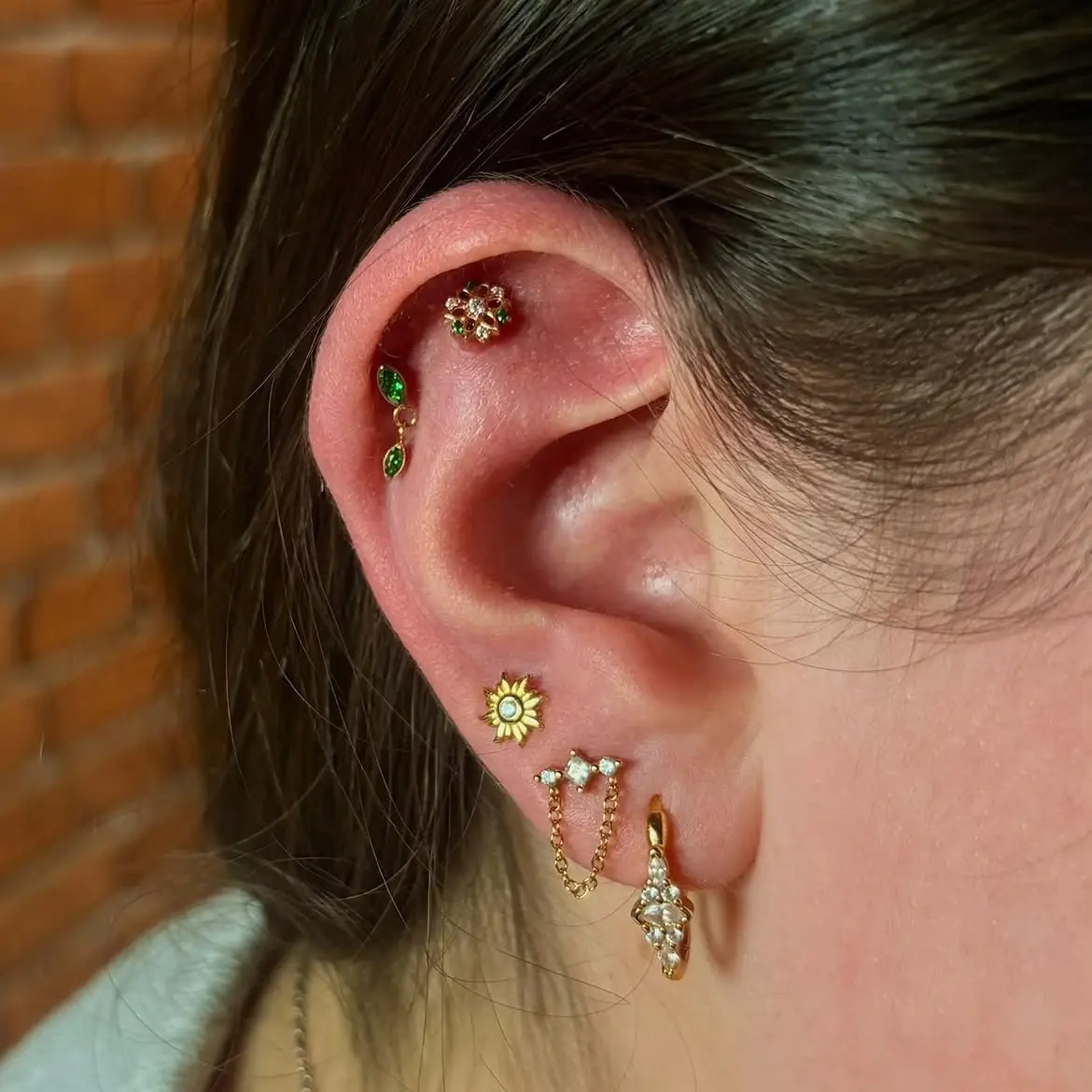 Composition de piercings avec bijoux verts, réalisée au salon Ino-Ink