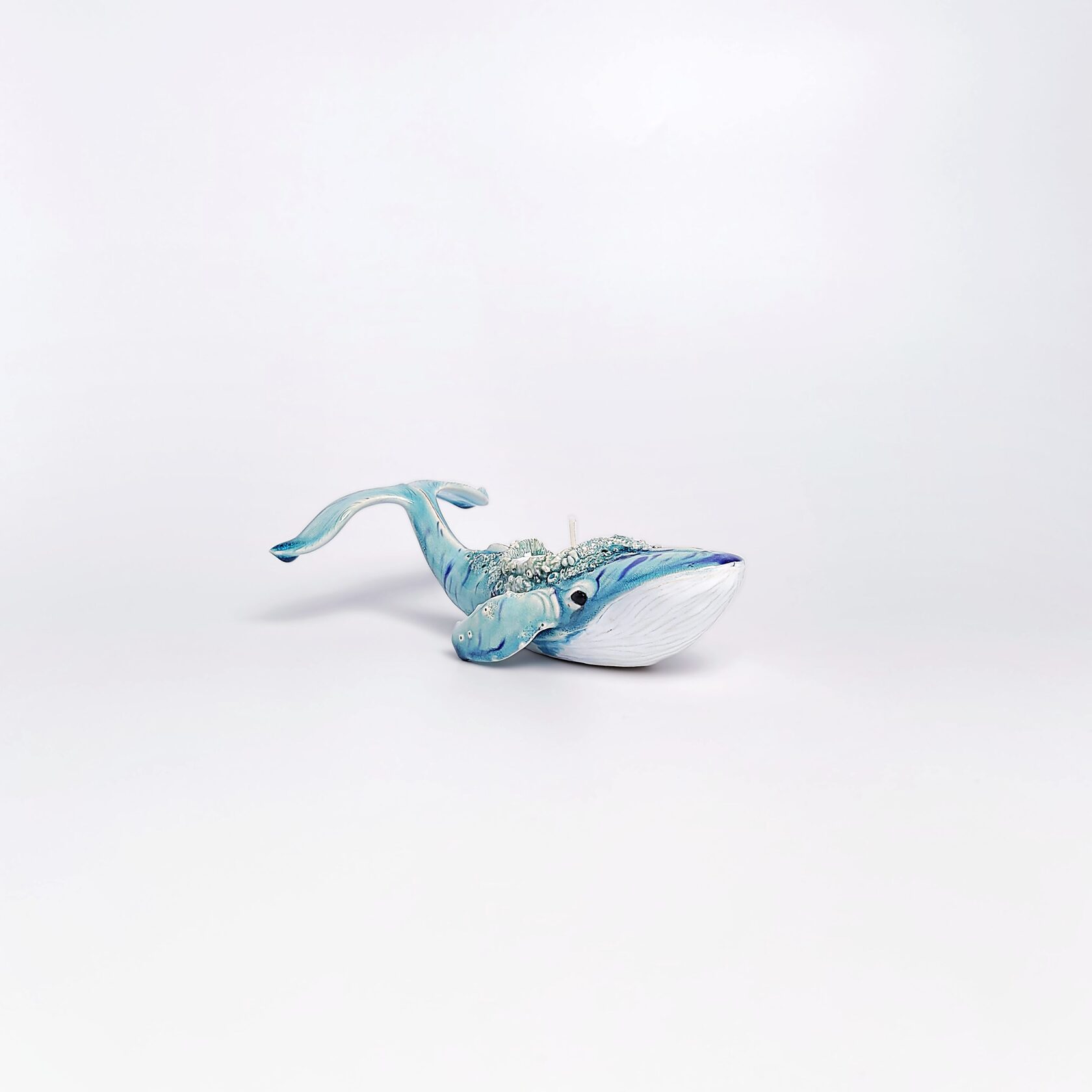 Unique handmade ceramic whale candle holder with ocean-blue glaze, detailed sculptural texture, and a built-in candle