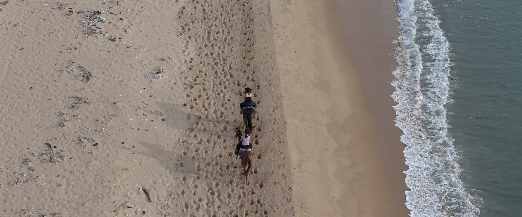 Two riders on the shore near Punanai, seen from above.